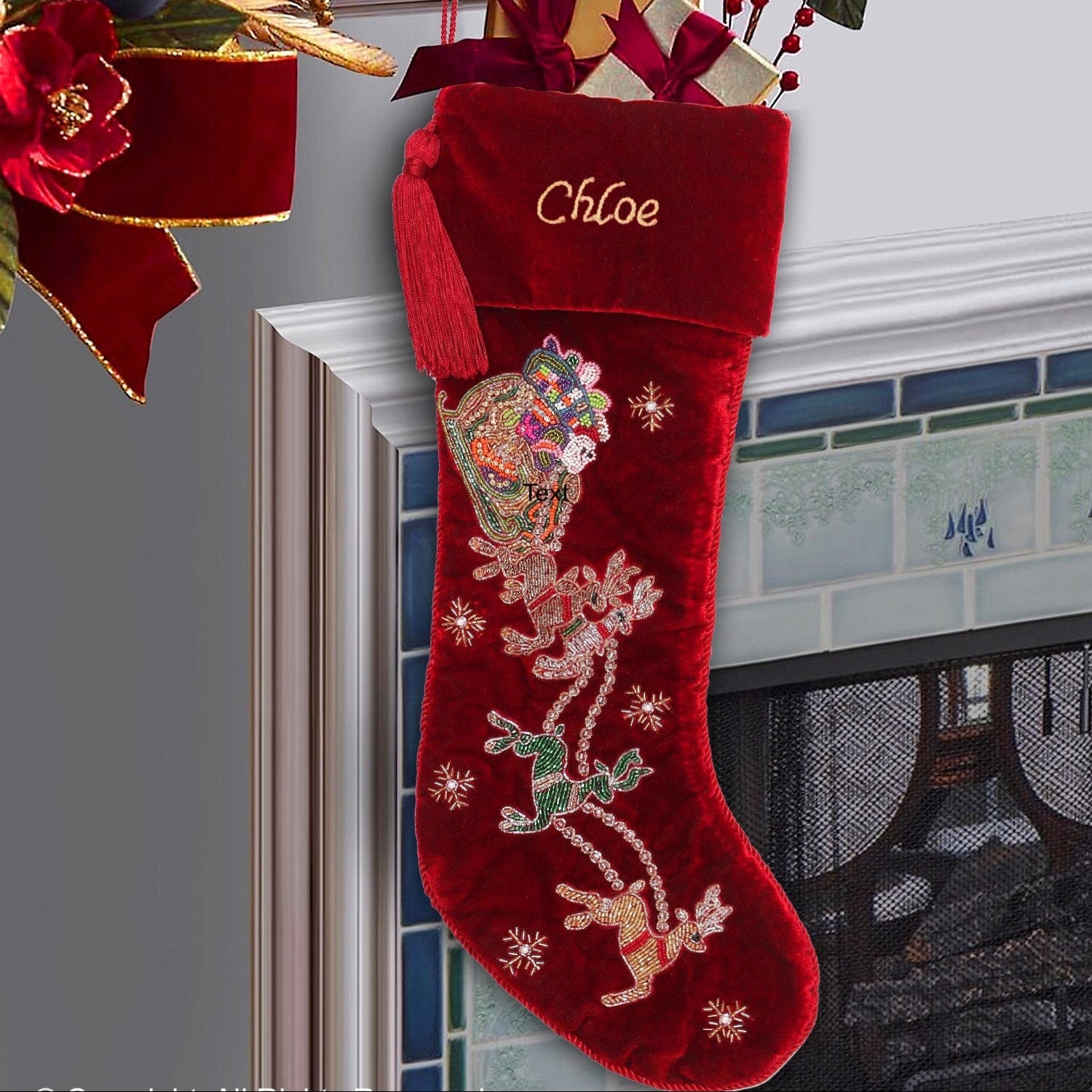 A red velvet Christmas stocking with hand beading and golden embroidery, hanging by the fireplace, personalized with the name 'Chloe'.
